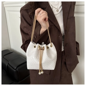 Dettaglio borsa a secchiello intrecciata bianca con coulisse di perle e catene dorate