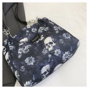 Detail of gothic tote bag with skull floral print, silver chains, and fashion tag