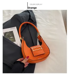 Detail of orange crescent bag featuring crocodile embossed leather and gold metal buckle