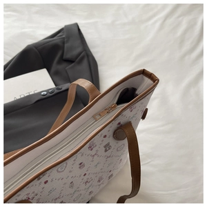 Top view of cream tote bag with pink bear patterns and brown zipper closure detail