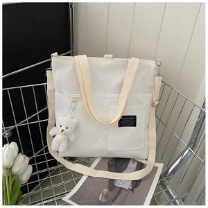 Detailed shot of a white canvas tote bag in a metal cart with a cute plush bear charm