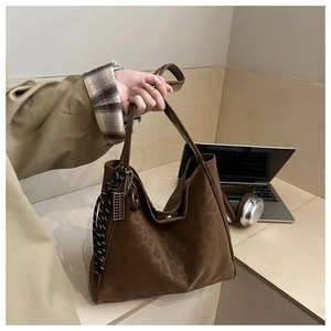Brown suede tote bag with leopard pattern and braided charm detail in a lifestyle setting