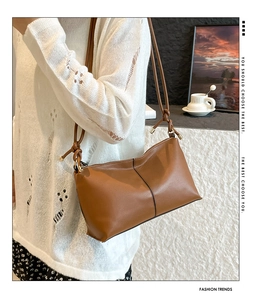Brown leather shoulder bag with decorative knotted strap and metal end detail on model