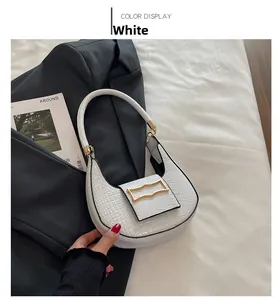 White crescent underarm bag with crocodile pattern and golden buckle on dark suit jacket