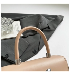 Detailed close-up of smooth beige leather handbag with silver metallic handle hardware