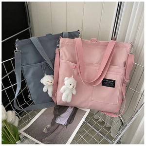 Detailed view of canvas tote bags with adjustable straps and cute plush bear charms