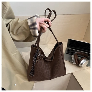 Detail of dark brown leopard pattern tote bag with tassels in a workspace setting