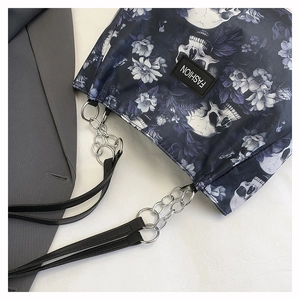 Detail of gothic tote bag showing floral skull print and silver chain link strap design