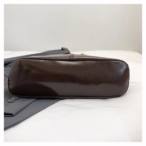 Detail view showing the flat oval base and fine stitching of the dark brown leather tote bag