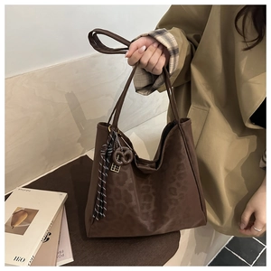 Detail of dark brown faux suede tote bag with leopard pattern and striped tassel charm