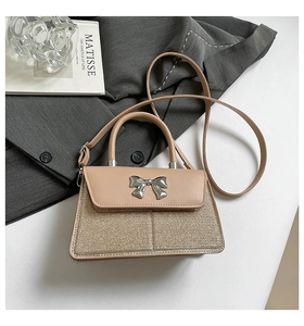 Detail of glittery fabric handbag with silver bow metal buckle on a grey blazer