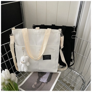 Detail of canvas tote bags with adjustable strap and cute plush bear charm in a cart