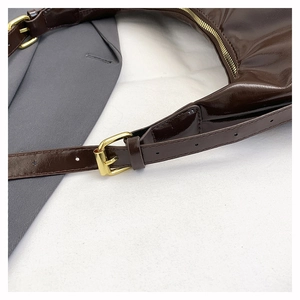 Detailed view of dark brown glossy tote bag with adjustable strap and gold metal zipper