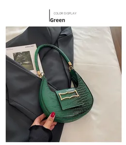 Detail of emerald green faux crocodile skin texture and gold buckle on hobo bag