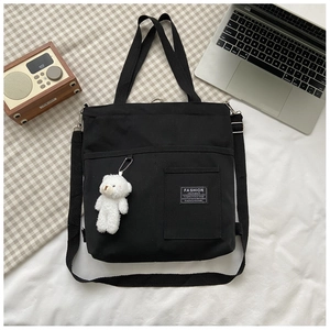 Detail of black canvas tote with Fashion Instinct label and cute plush bear charm