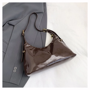 Macro view of dark brown high-gloss patent leather hobo bag with gold hardware