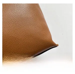 Close-up of premium brown lychee pattern leather texture on a bucket tote bag
