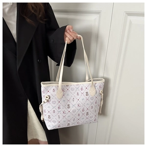 Detail of printed tote bag featuring pink cartoon motifs and beige leather handles