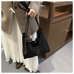 Detail of dark leopard print tote bag with tassel drawstring and round wood charm