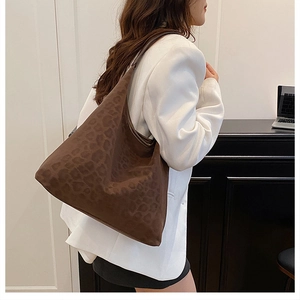 Detail of a large leopard print tote bag with suede texture on a model in white blazer