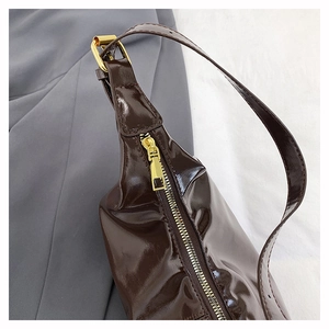 Detail view of glossy dark brown leather tote with premium gold-tone zipper and stitching