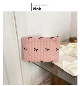 Detailed view of pink quilted handbag with black bow embroidery and zip closure