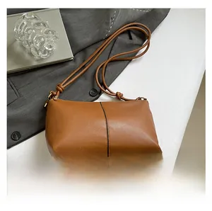 Detail of caramel leather shoulder bag featuring knotted strap and vertical stitching design