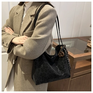 Detail of black leopard print tote bag with metal charm and slender shoulder straps