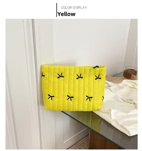Detail of yellow quilted corduroy pouch with butterfly embroidery and black zipper