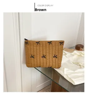 Close-up of quilted brown corduroy makeup bag featuring black butterfly embroidery