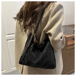 Detail of black leopard pattern nylon tote bag with decorative woven lanyard and metal charm