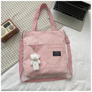 Detail of pink canvas bag featuring a front pocket, brand label, and cute bear pendant