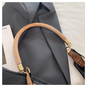 Detail of snake skin pattern handle and golden metal ring connector on black leather bag