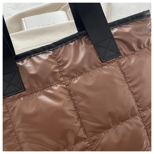 Détail d'un sac cabas matelassé marron avec des anses solides en nylon noir de qualité