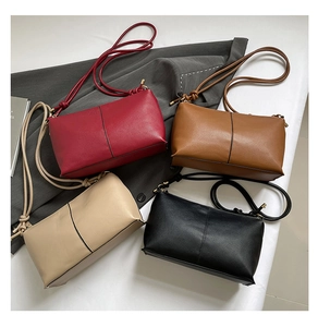 Minimalist leather crossbody bags in four colors arranged on a textured studio backdrop