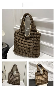 Detailed close-up of quilted puffy tote bag in brown with soft padded handles and texture