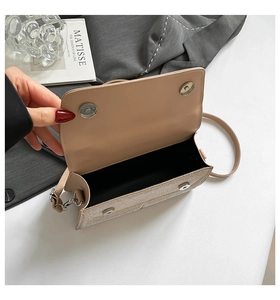 Detail view of beige crossbody bag with dual magnetic closures and shimmering texture