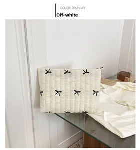Close-up of cream quilted corduroy clutch with black butterfly embroidery and zipper