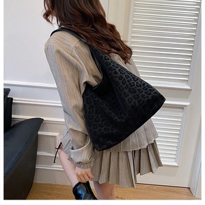 Detail view of oversized black leopard print tote bag on a model in a luxury interior