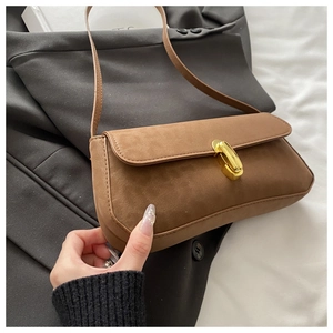 Gros plan du sac baguette en daim marron avec une boucle en métal doré minimaliste