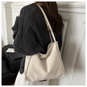 Detail of creamy white tote bag showing soft textured leather and magnetic closure