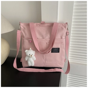 Detail of pink canvas tote bag featuring dual front pockets and cute bear plush charm
