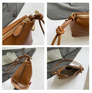 Detail of brown pebbled leather shoulder bag with golden zipper and knot strap detail
