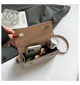 Internal view showing capacity of beige bow shoulder bag with phone and lipstick items