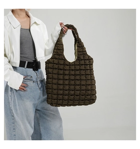 Close-up of deep olive puffy quilted tote bag with large square stitching and soft texture