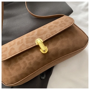 Détail d'un sac baguette léopard en simili daim avec boucle en métal doré en forme de U
