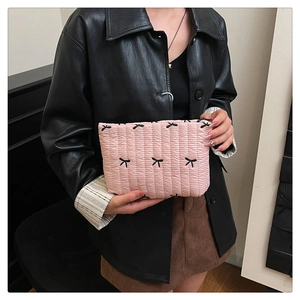 Detailed view of pink quilted handbag with black butterfly embroidery held by a model