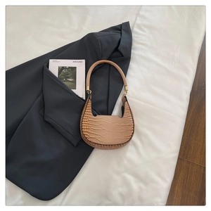 Detailed texture of crescent underarm bag with crocodile pattern and gold hardware