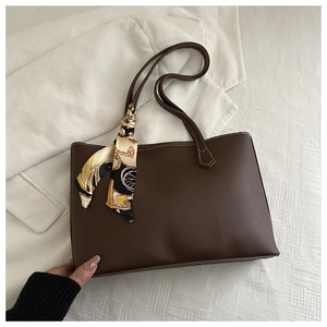 Detail of dark brown faux leather tote with white stitching and printed silk scarf