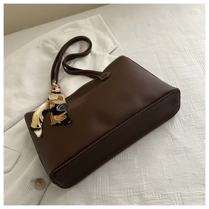 Detail of dark brown tote bag with decorative patterned silk scarf wrapped on handle